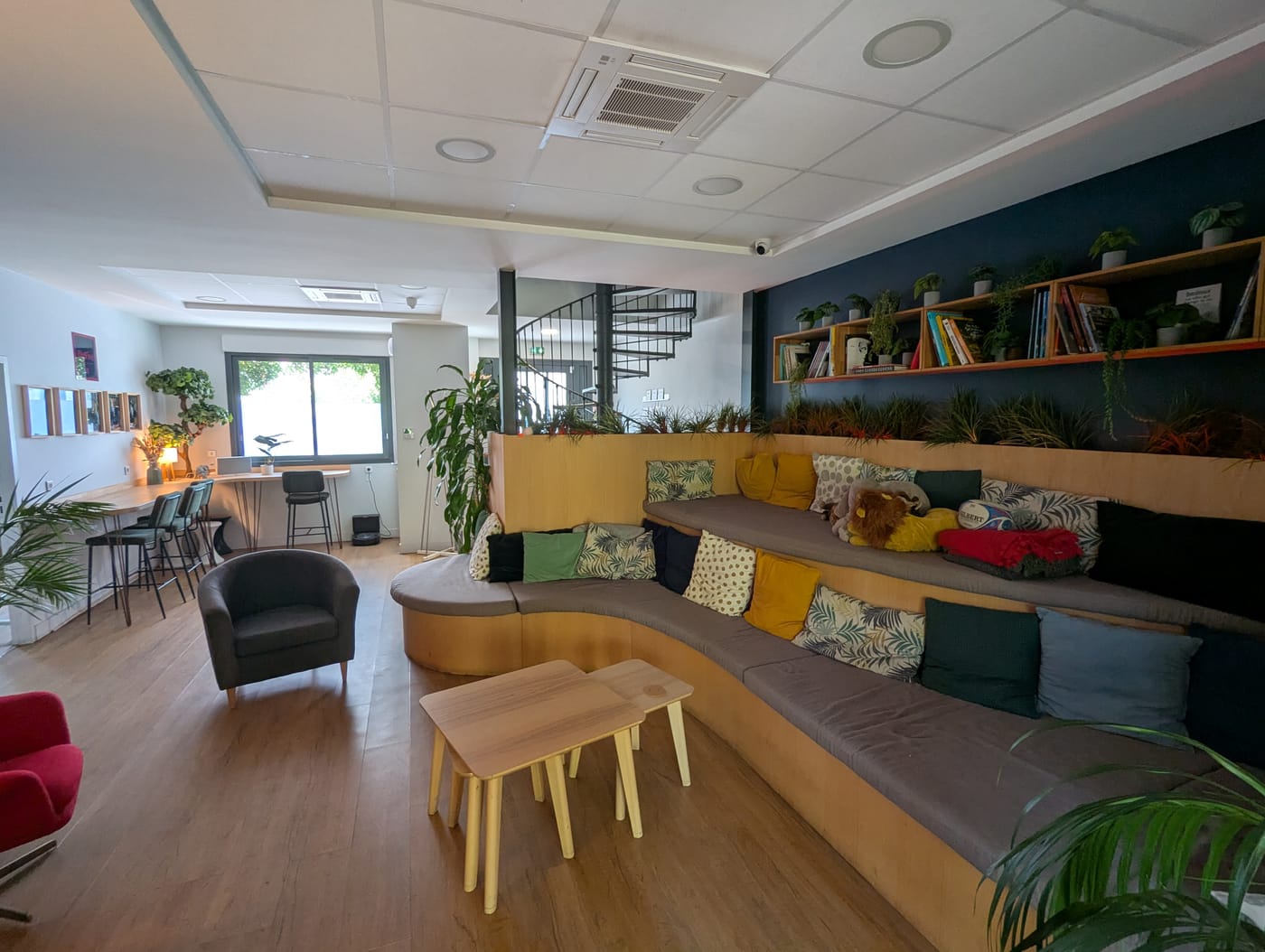 Espace lounge chaleureux avec gradins en bois, coussins colorés et tables basses