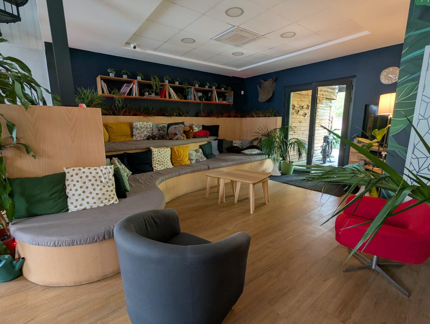 Espace détente convivial avec banquette en bois, coussins colorés, fauteuils et plantes chez BigFive à Bordeaux