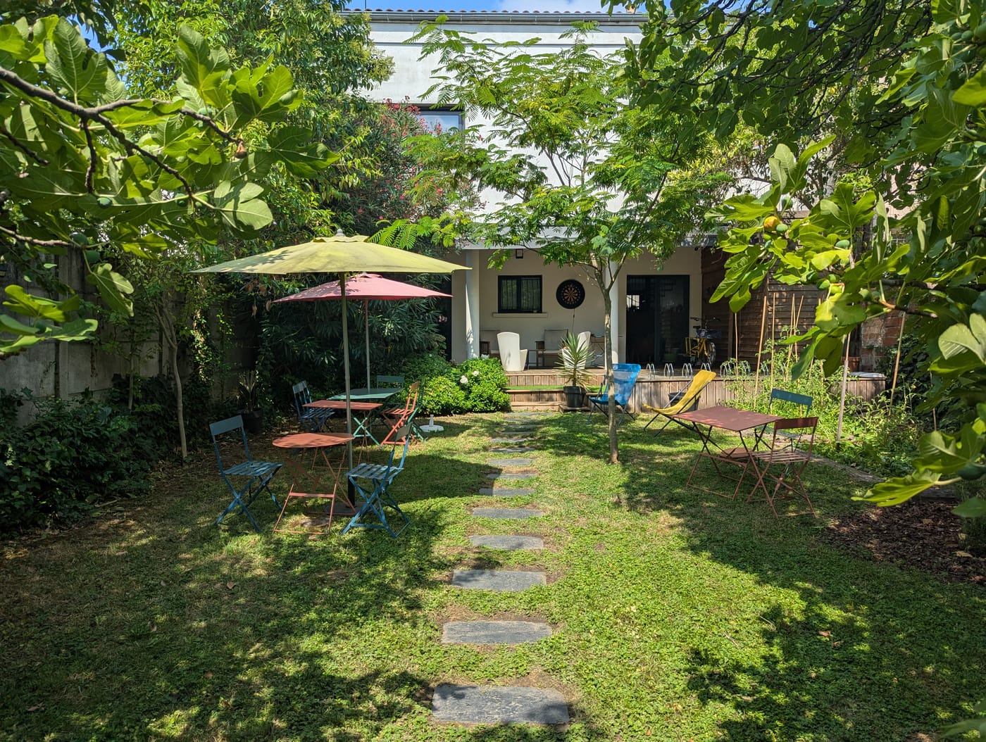 Jardin arboré et verdoyant avec des tables de café et des parasols chez BigFive à Bordeaux
