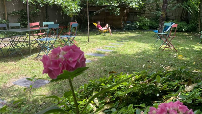 Jardin arboré verdoyant du coworking aux Chartrons à Bordeaux avec des chaises de couleur et une table