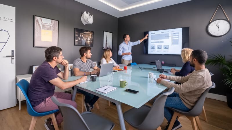 Équipe en réunion de brainstorming autour d'une grande table dans un espace de coworking lumineux