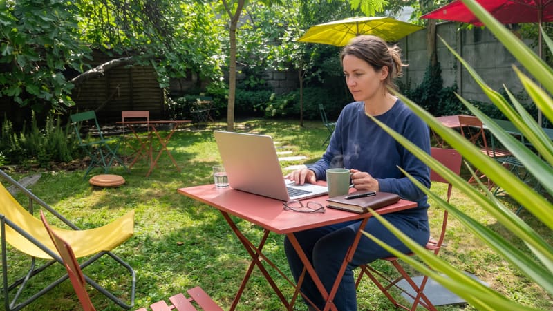 Une femme en télétravail sur son ordinateur portable dans un jardin arboré de Bordeaux