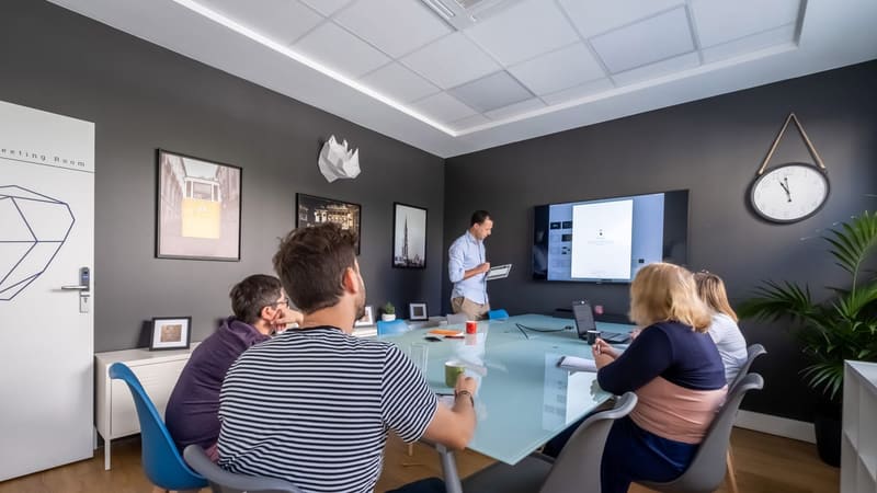 Salle de réunion lumineuse et éco-responsable avec grand écran et collaborateurs attentifs chez BigFive aux Chartrons